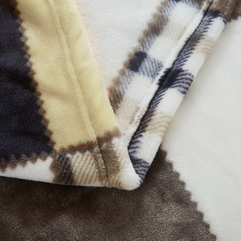 Close-up of plush plaid throw blanket edge with brown, cream, and navy accents