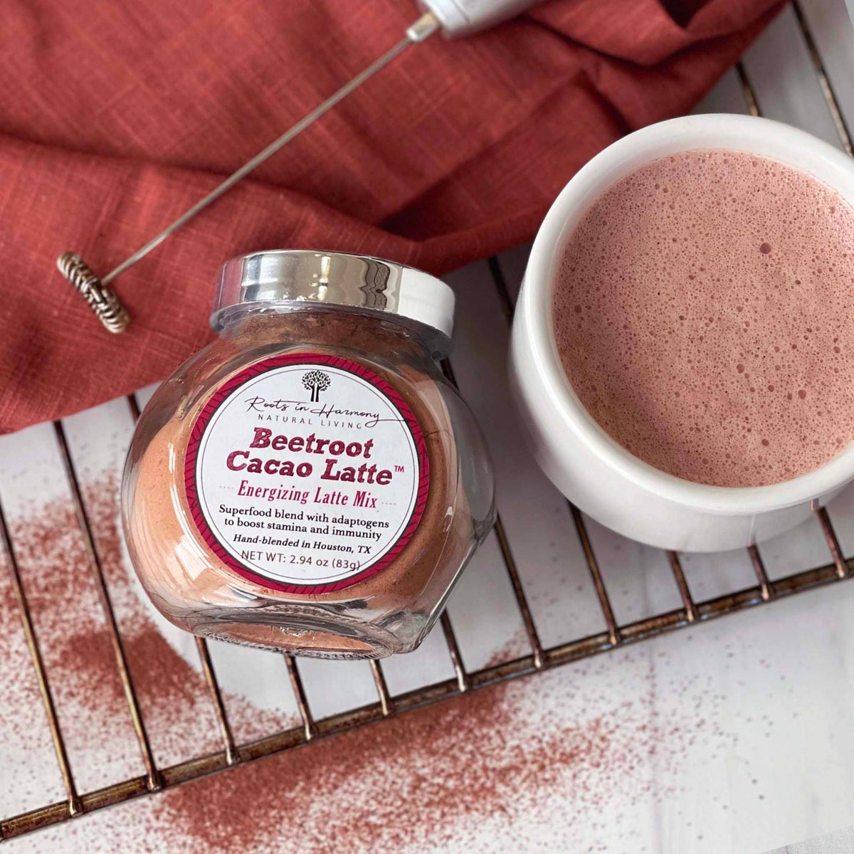 Beetroot cacao latte mix jar with lid and frothy latte in a white mug