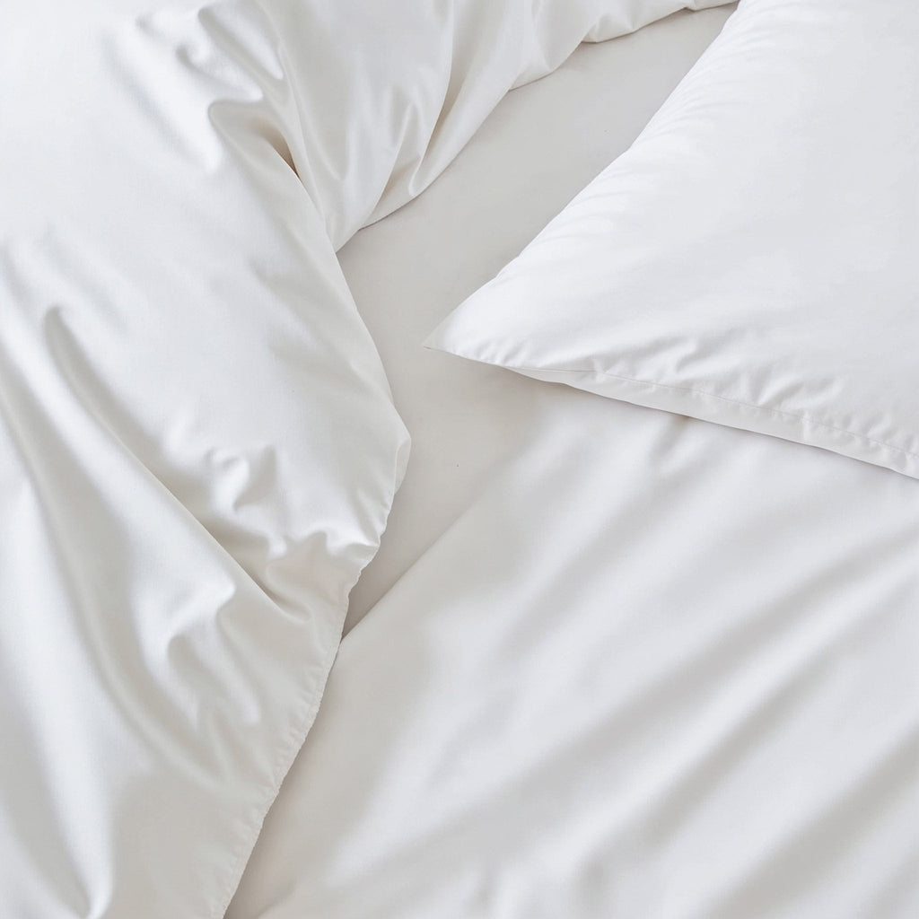 White sateen duvet cover close-up showing glossy fabric texture and stitched seam