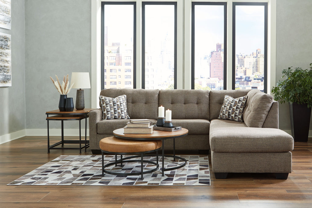 Light gray corner chaise sectional with tufted seat and two patterned accent pillows