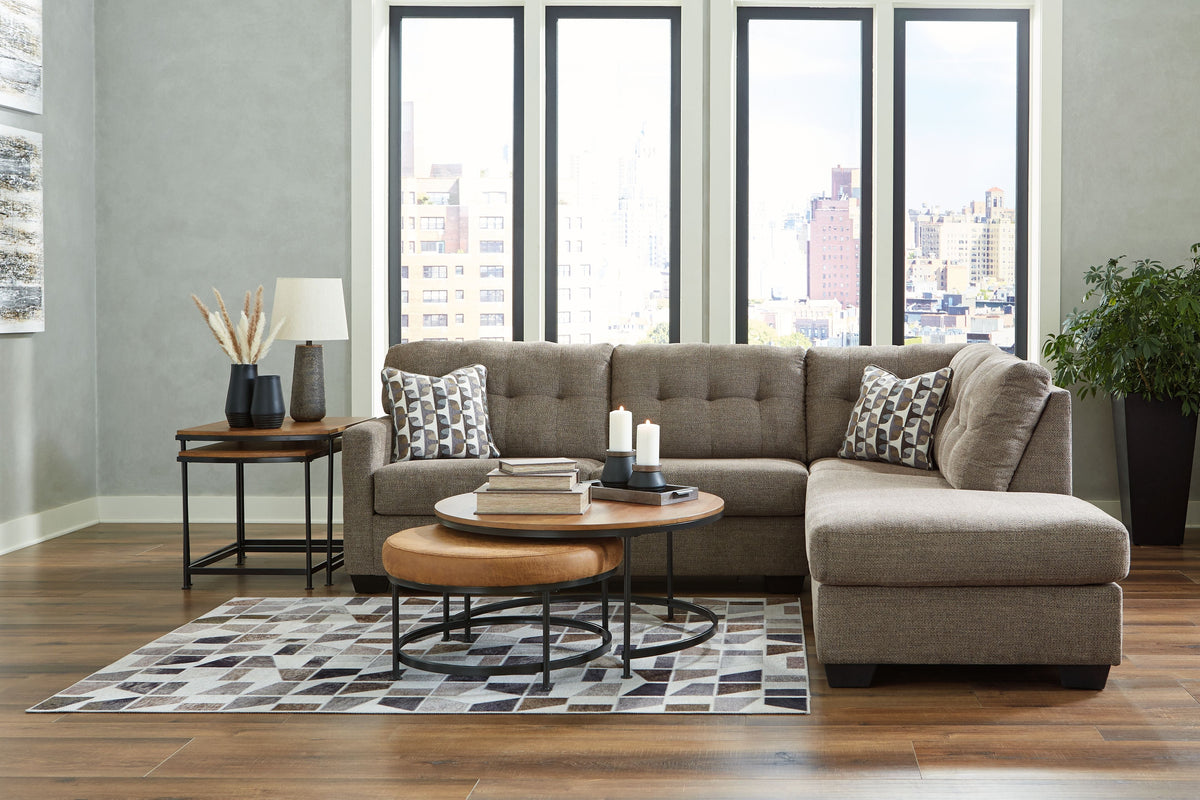 Light gray corner chaise sectional with tufted seat and two patterned accent pillows