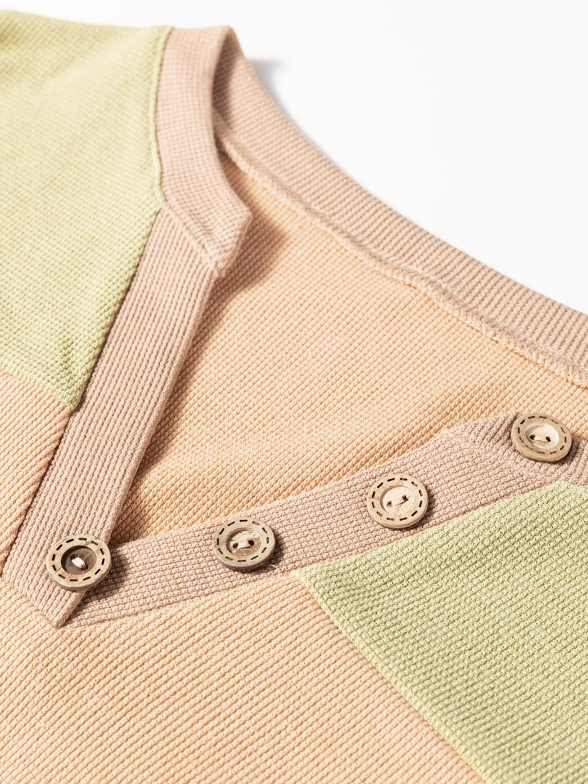Close-up of thermal henley neckline with snap buttons and color-block knit texture