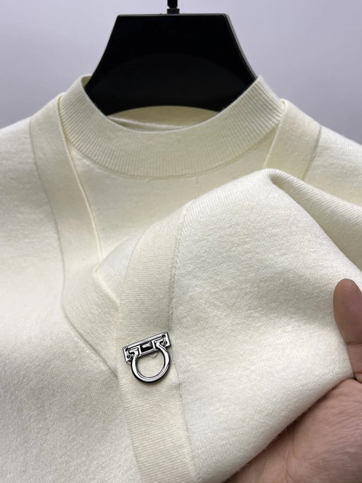 White knit sweater close-up: ribbed collar and ring-loop closure at chest