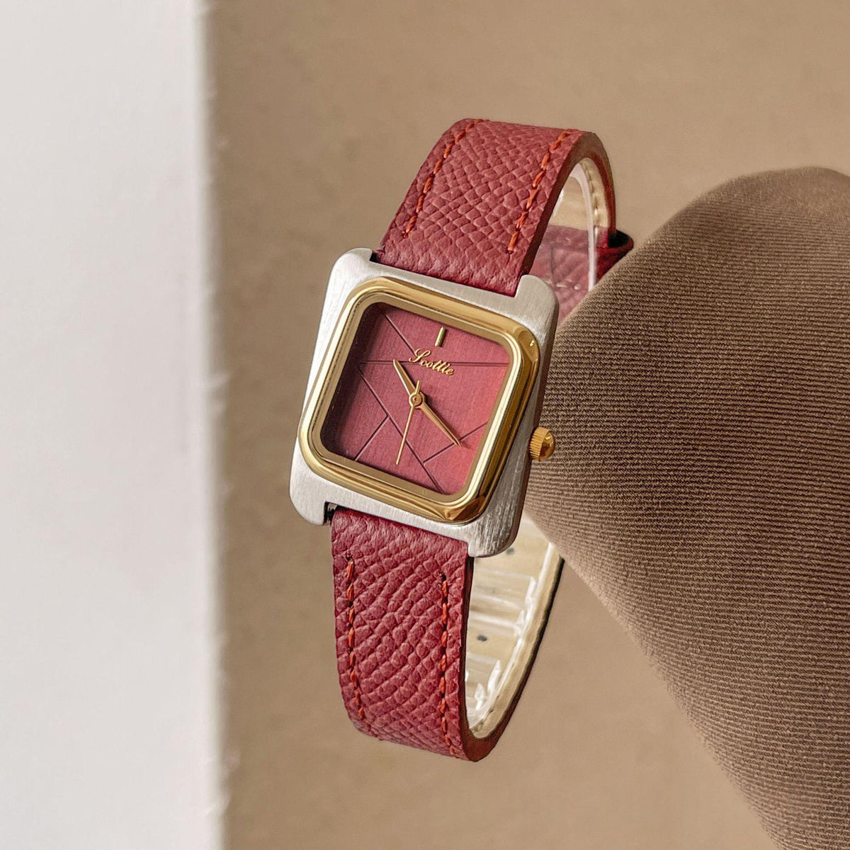 Square quartz watch with gold case, burgundy leather strap, maroon dial