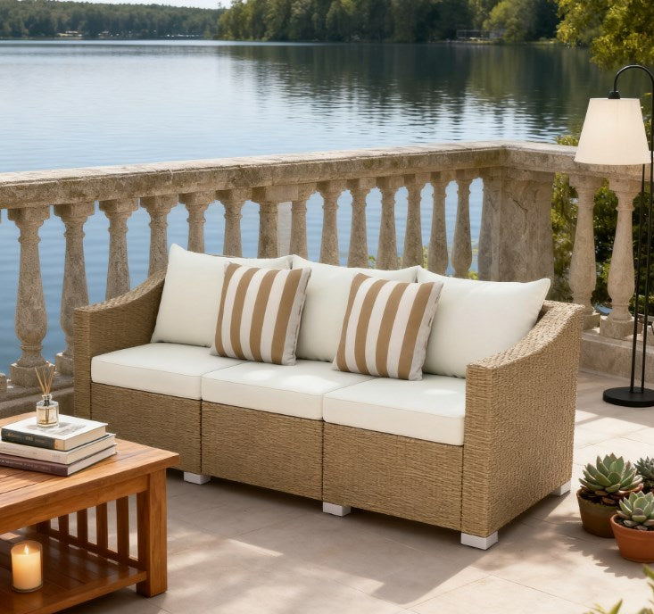 Outdoor rattan sofa with beige woven frame, white cushions, and striped throw pillows
