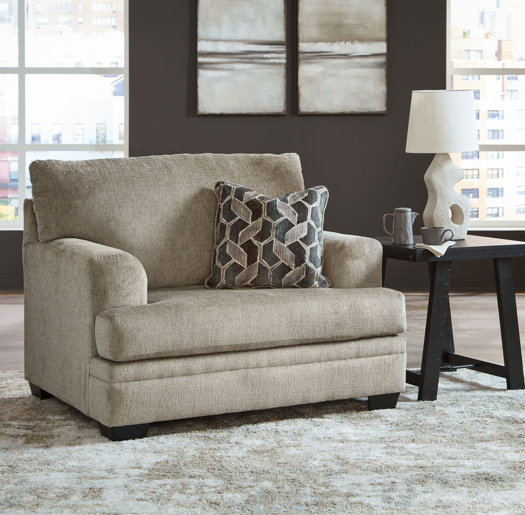 Beige upholstered chair with geometric patterned throw pillow and black feet