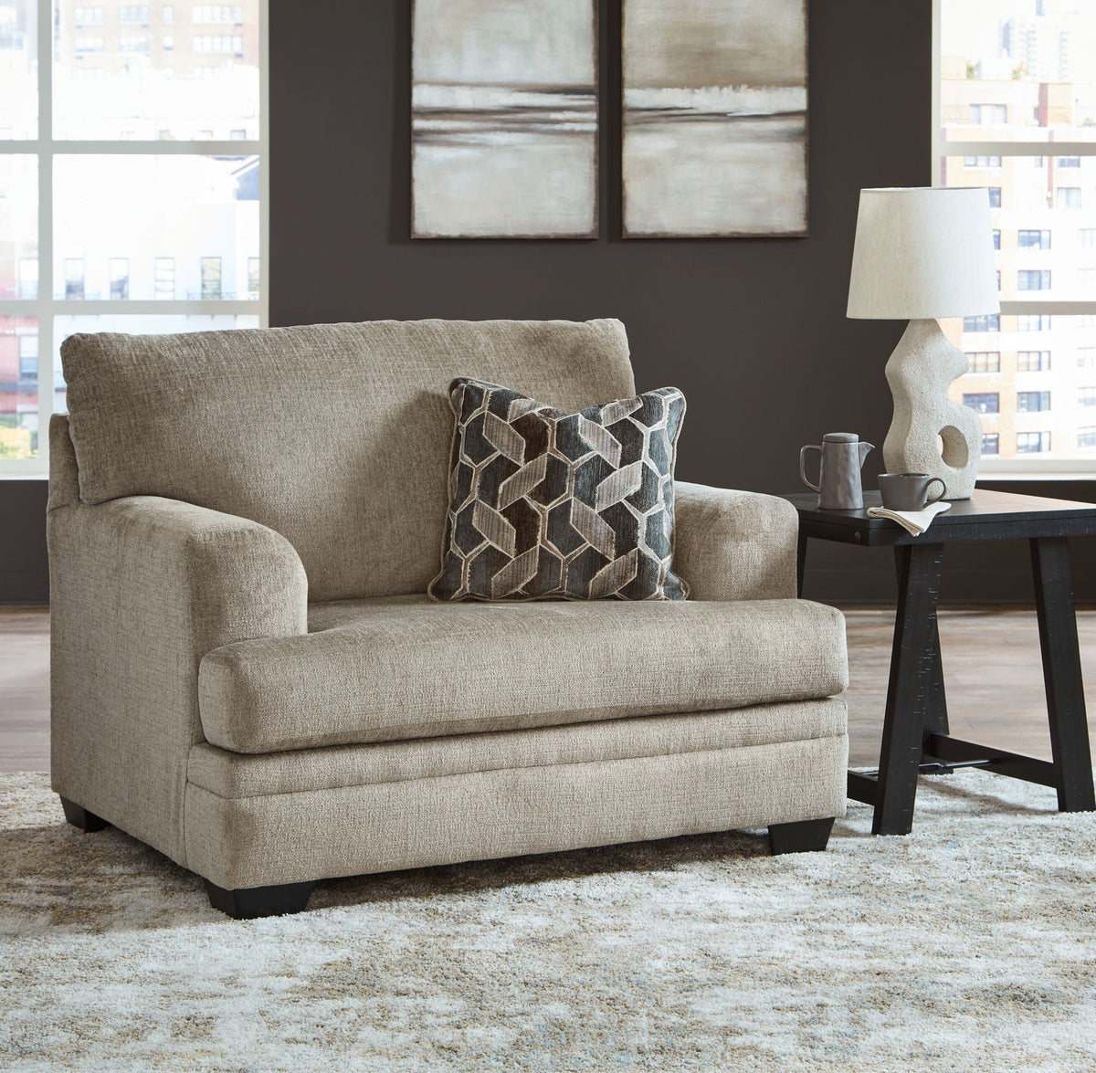 Beige upholstered chair with geometric patterned throw pillow and black feet