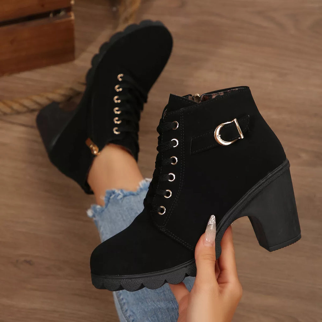 Black lace-up ankle boots with buckle strap and chunky block heel, close-up.