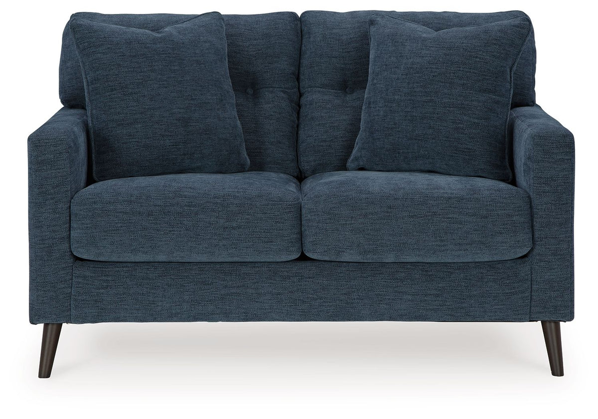Blue upholstered sofa with wide arms, three back cushions, and tapered wood legs