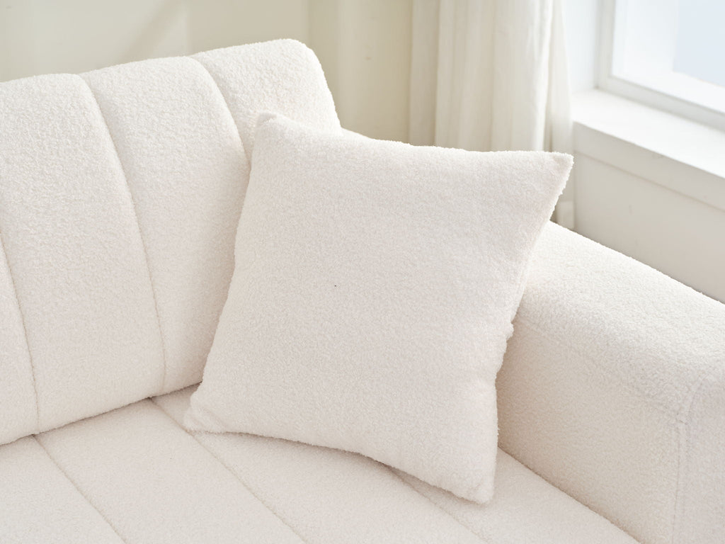 Beige sofa chaise seat with square throw pillow and ribbed back cushions.