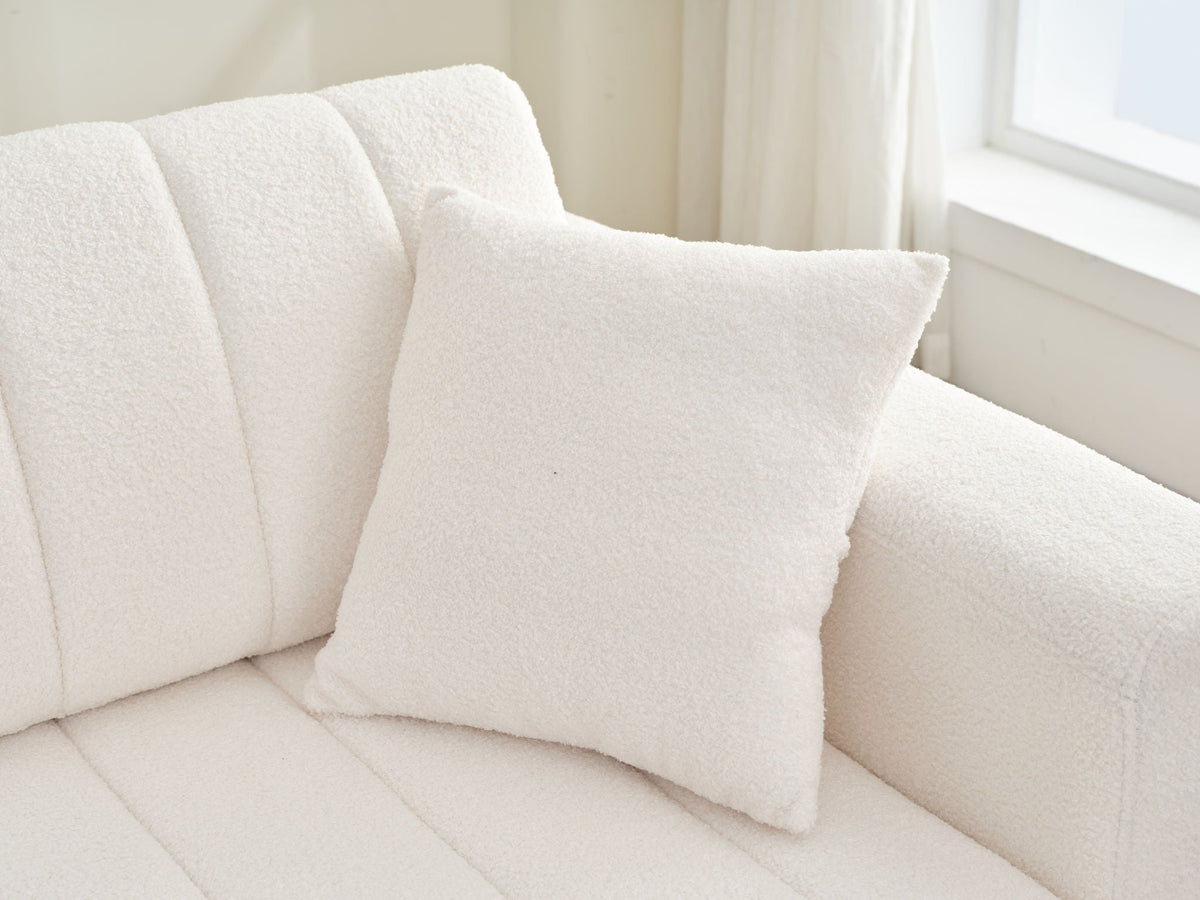 Beige sofa chaise seat with square throw pillow and ribbed back cushions.