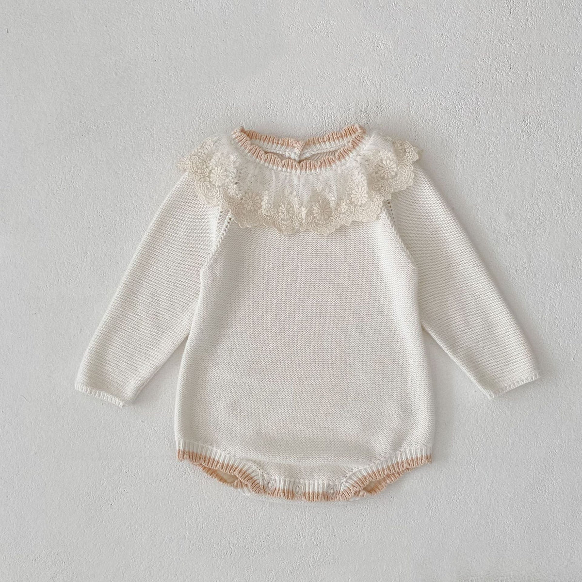 Off-white knitted baby romper with lace collar and long sleeves; ribbed hem edge