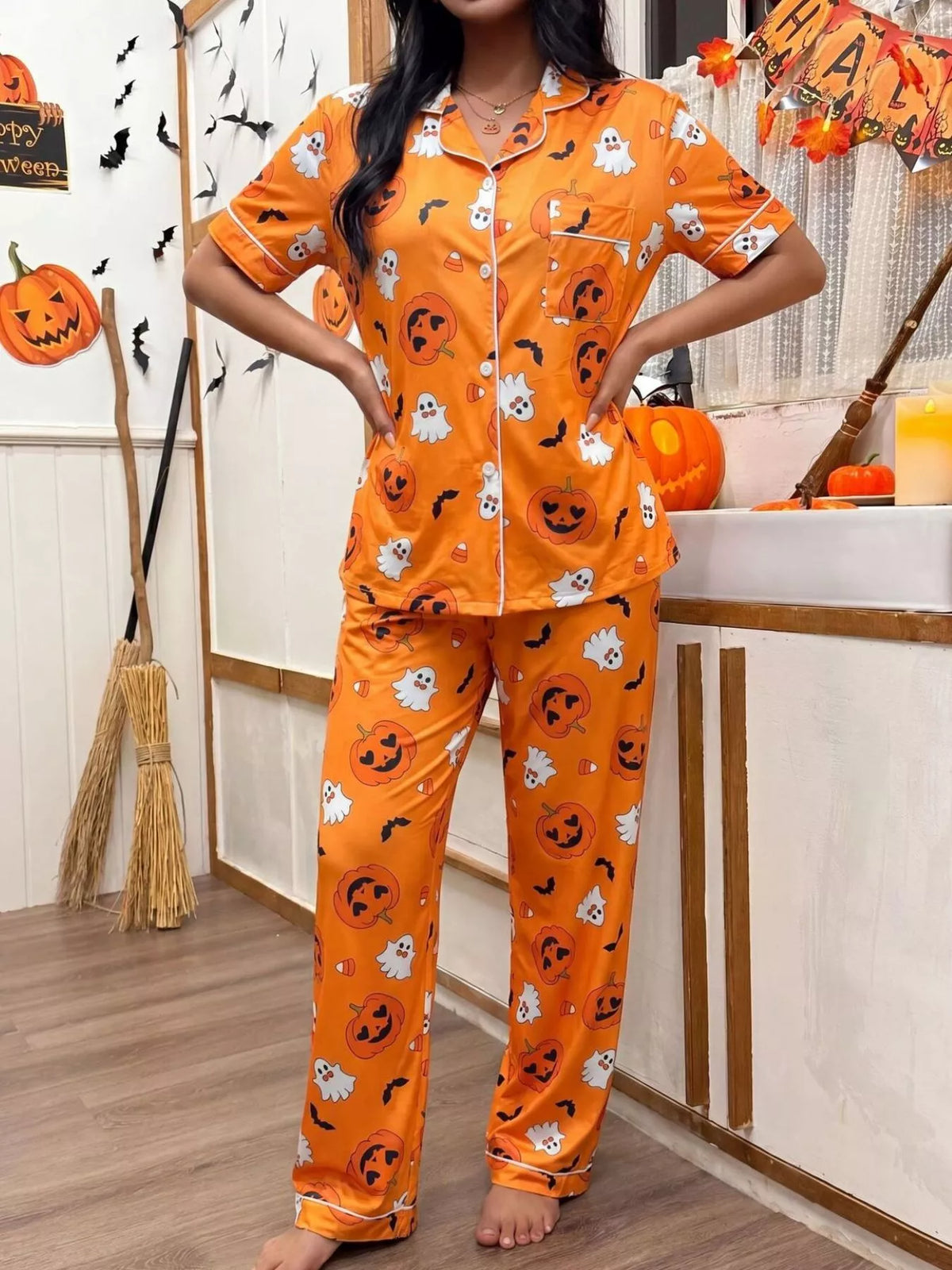 Orange pajama set with pumpkin, ghost, and bat prints, short-sleeve button-front top and pants