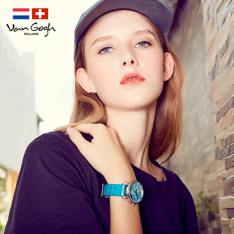 Women's quartz watch on wrist with turquoise band and teal floral dial detail.