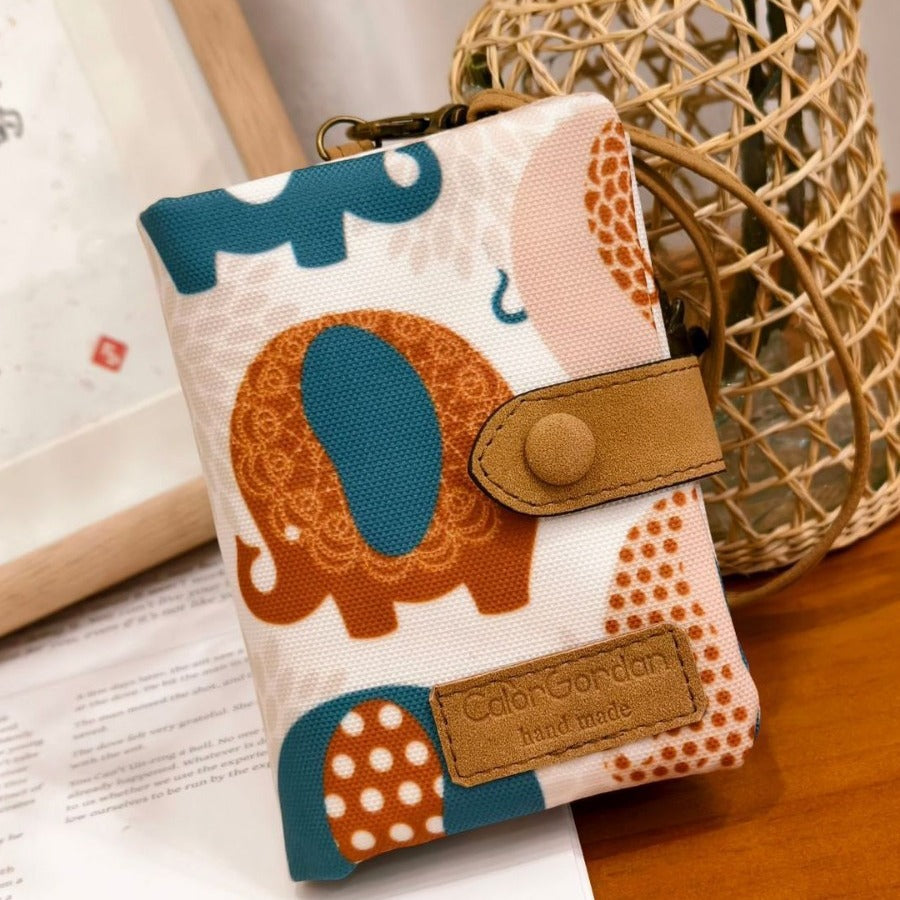 Printed tri-fold wallet with snap button, teal and brown elephant pattern, leather tab