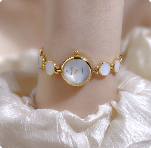 Gold watch bracelet with white oval shell links and round bezel dial