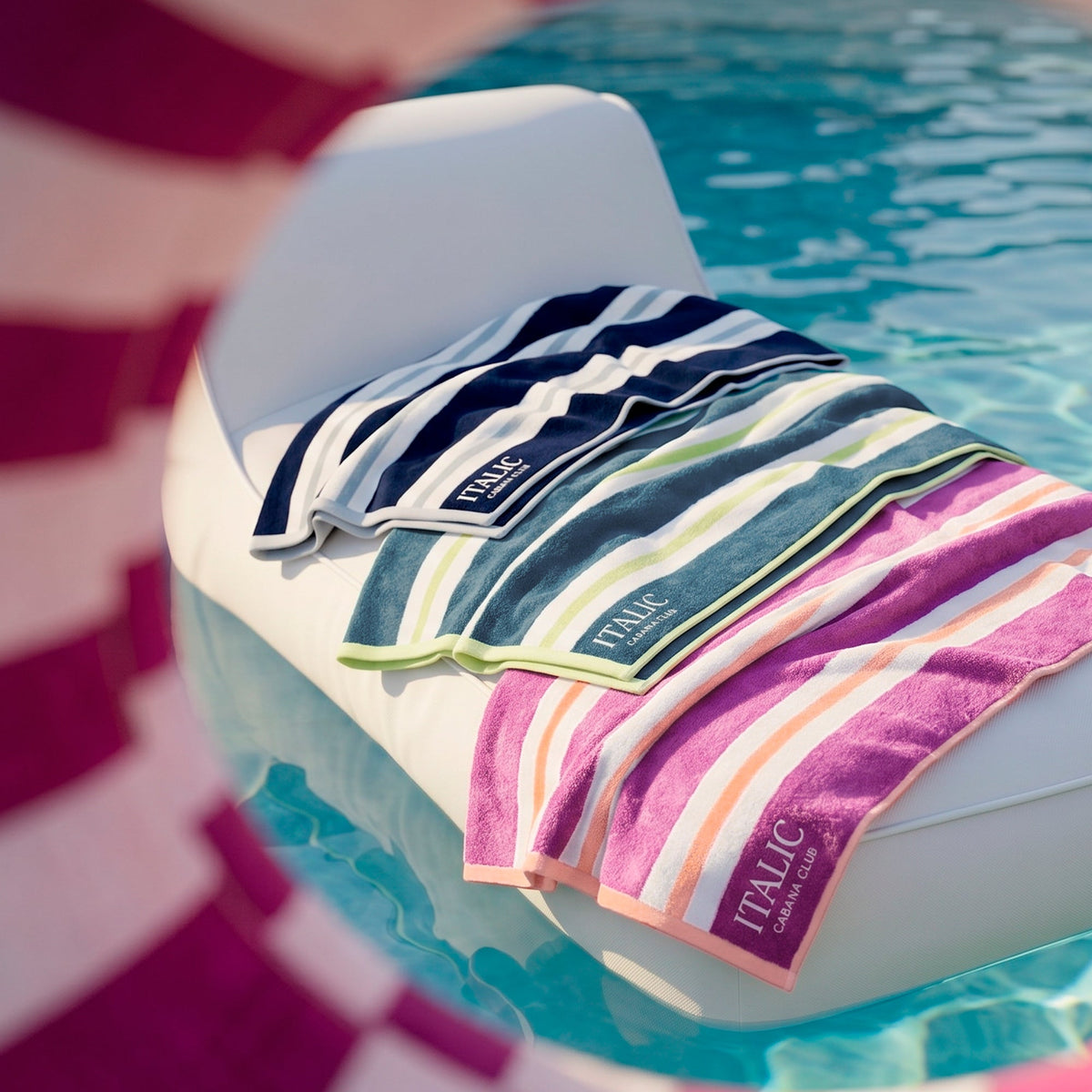 Stack of folded cotton beach towels with multi-color vertical stripes, “ITALIC” tags