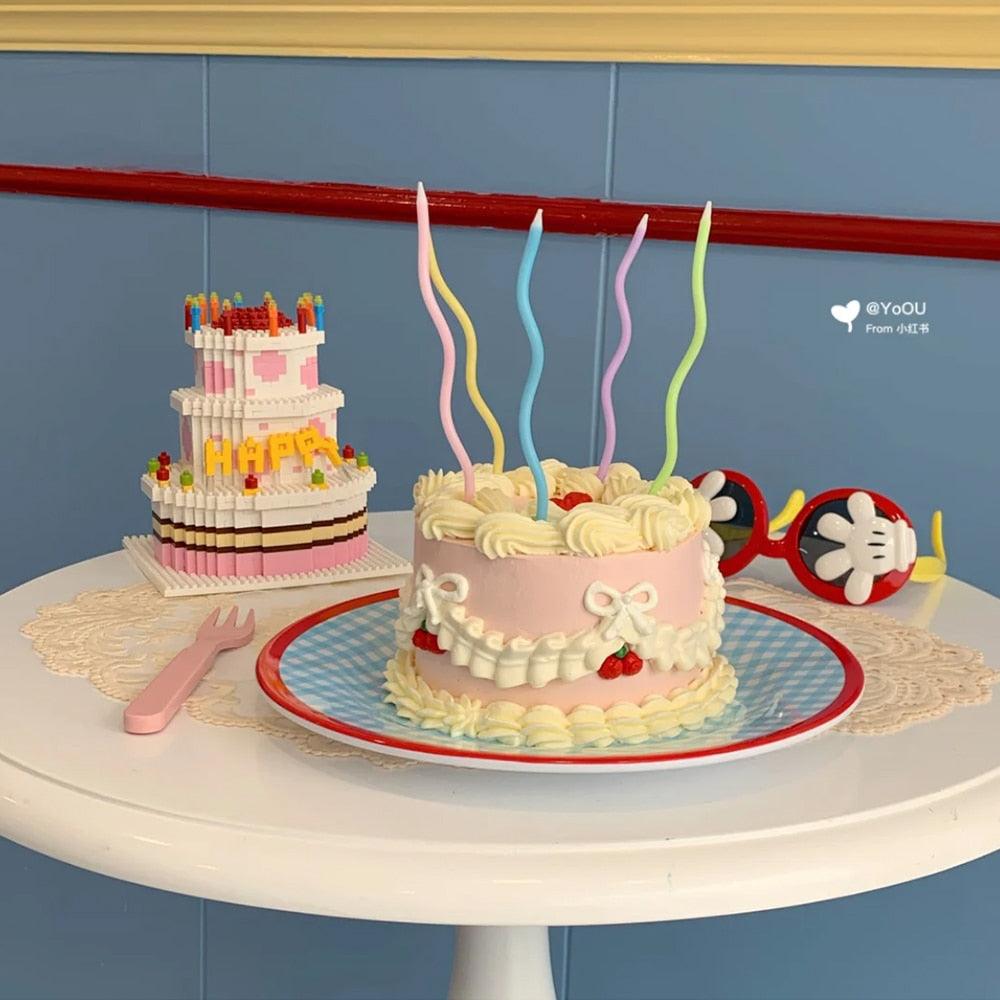 Numberless cartoon candles set with curved multicolor flames on frosted cake