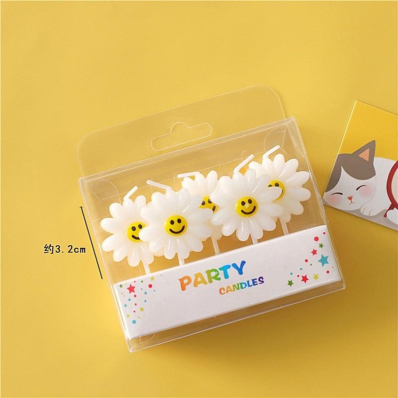 Cartoon party cake candles: three white daisies with yellow smiley faces in clear box