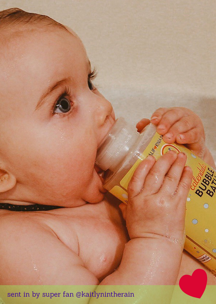 Baby sipping from a Calendula bubble bath bottle