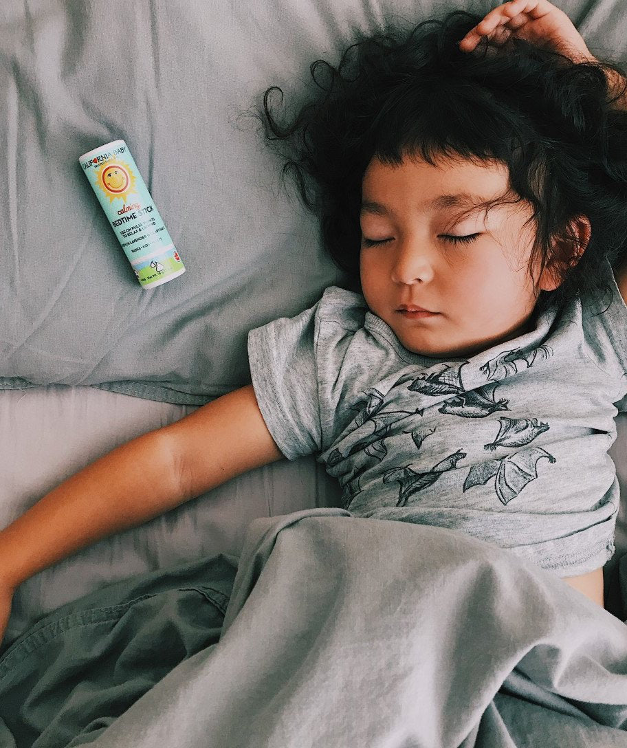 Calming Bedtime Stick tube on bed beside a sleeping child