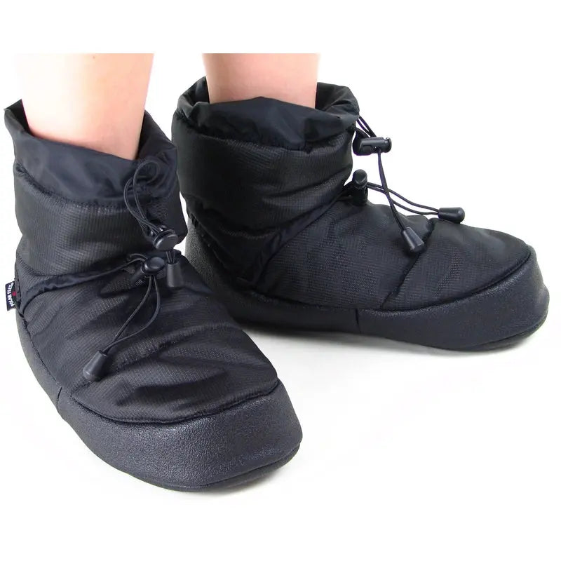 Black camp booties worn on feet, lace-up cuff and padded slip-on sole