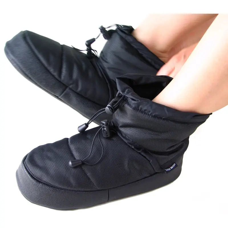 Black booties on feet with drawstring lacing across the top and thick sole