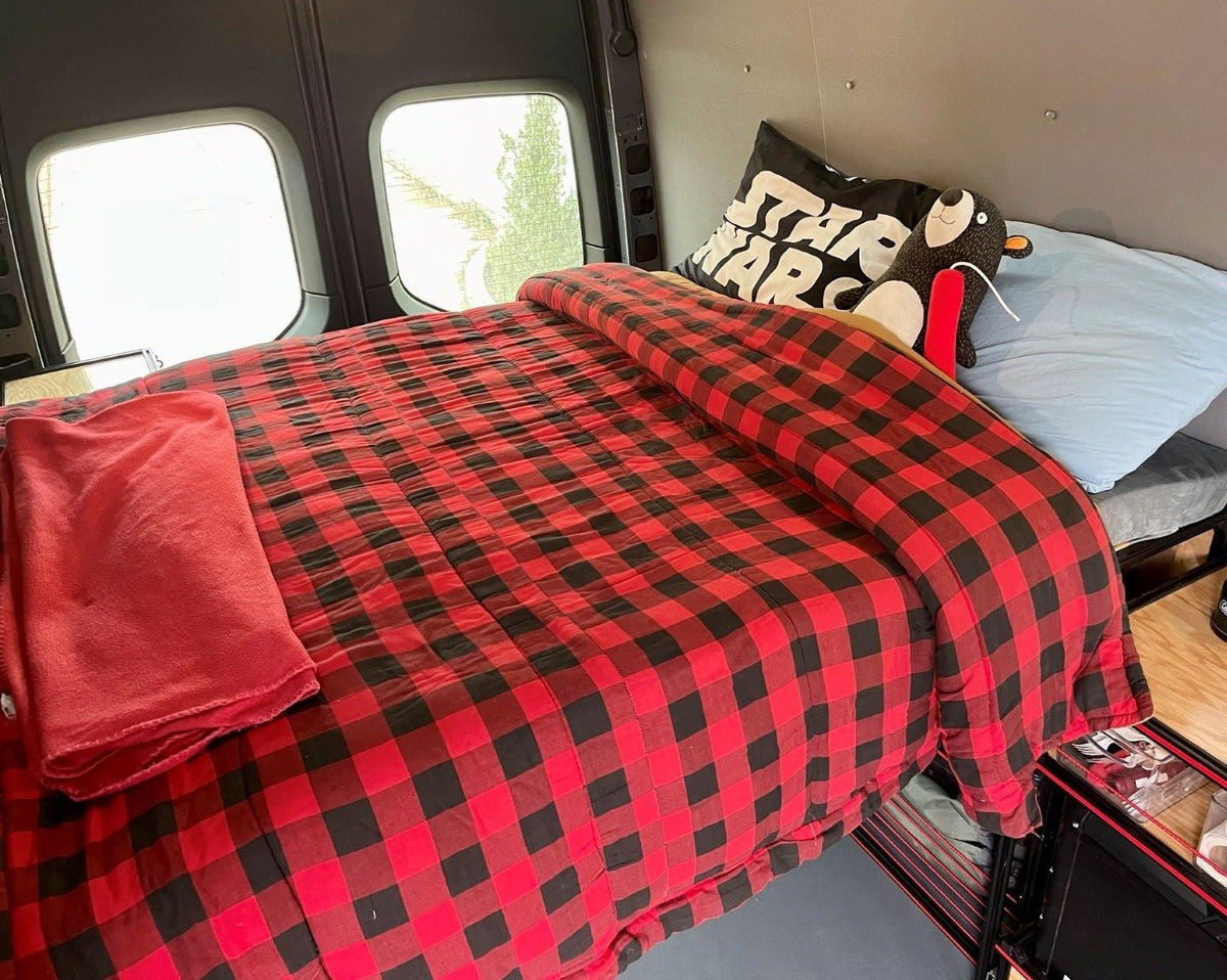 Van bed with quilted mattress and side access, featuring under-bed wire shelving storage