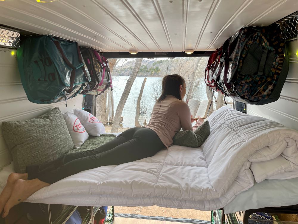 Van bed setup with mattress on top and metal wire shelving storage underneath