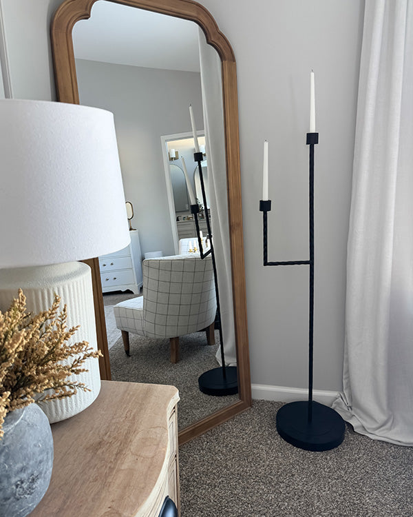 Black iron floor candelabra with two unlit candle holders and round base, matte.
