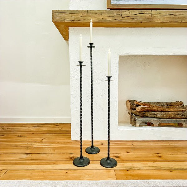 Set of 3 tall cast iron floor candle holders with round bases and spiked stems.