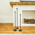 Set of 3 tall cast iron floor candle holders with round bases and spiked stems.