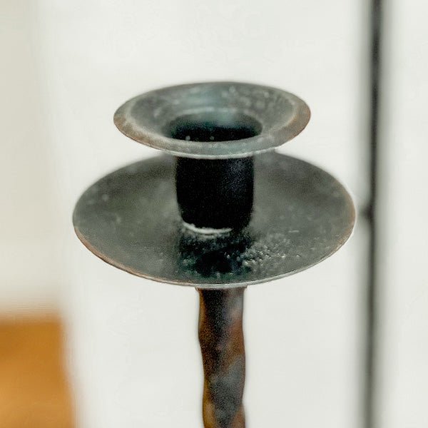 Close-up of the dark cast iron candle cup holder with wide circular saucer top.