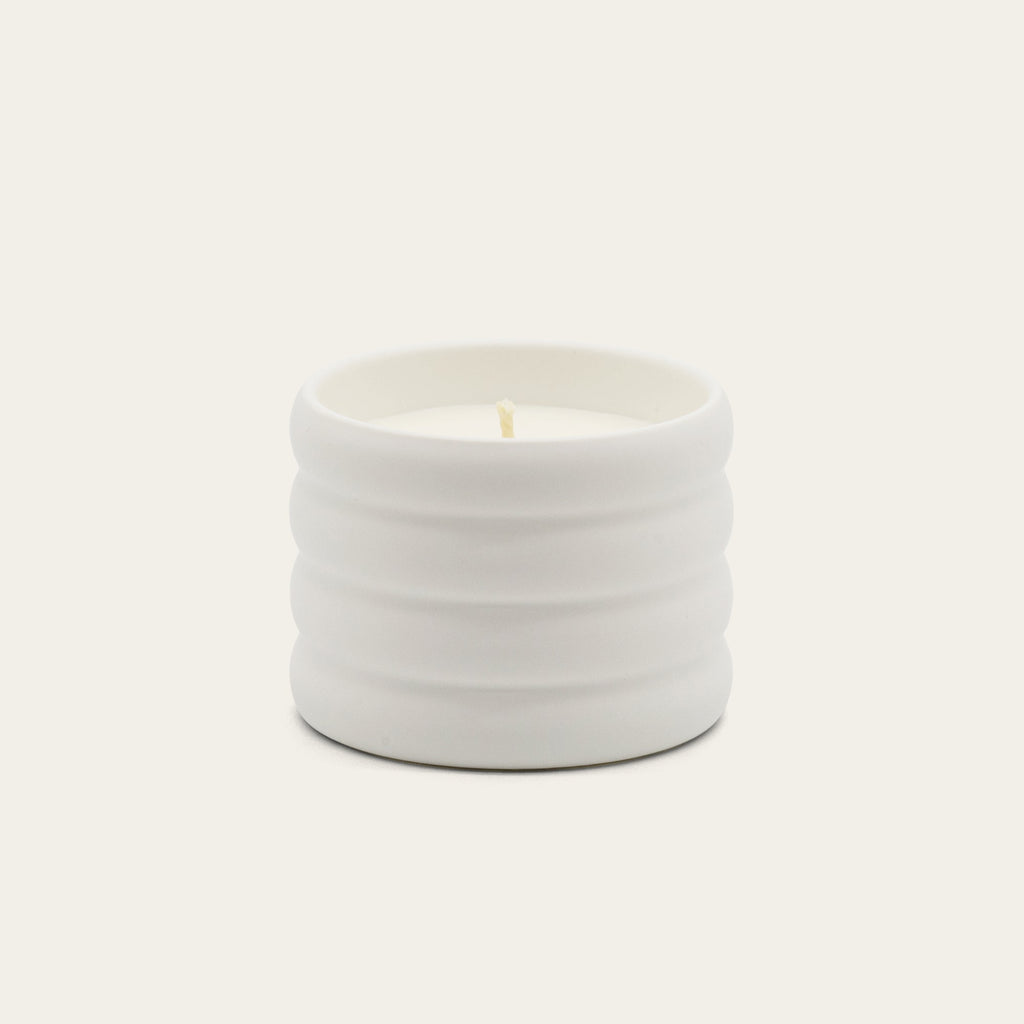 Soy wax ceramic candle in ribbed light-gray ceramic jar with flame.
