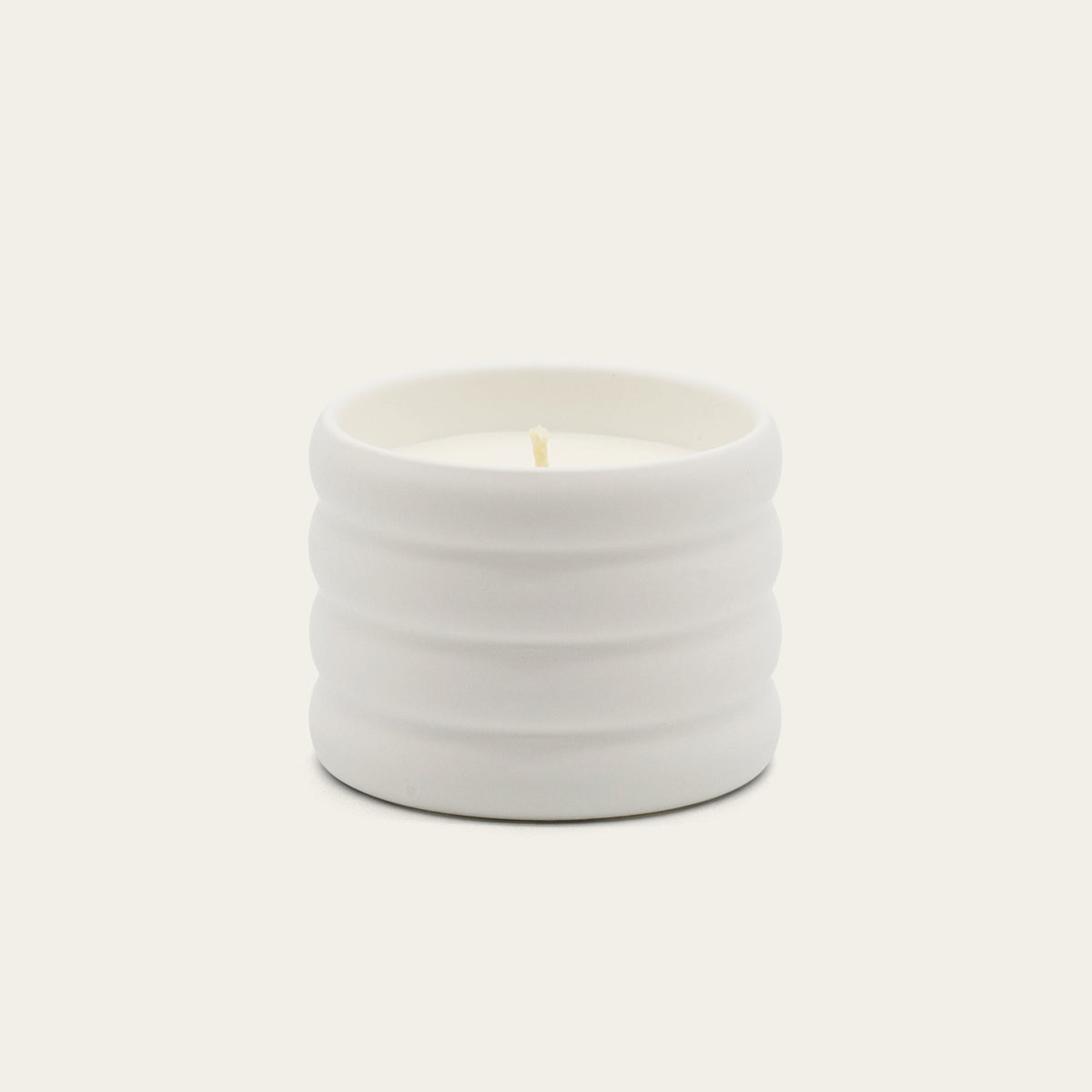 Soy wax ceramic candle in ribbed light-gray ceramic jar with flame.