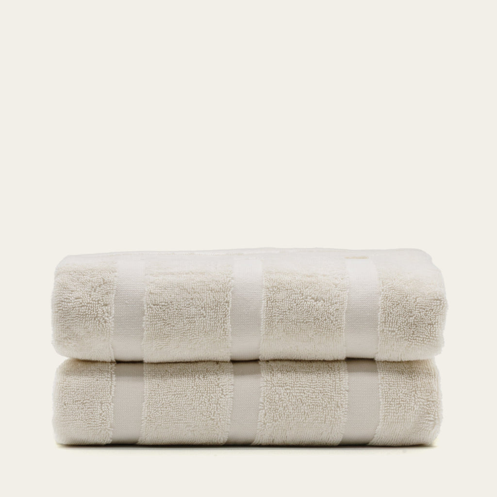 Rolled stack of cream cotton towels with embossed square texture