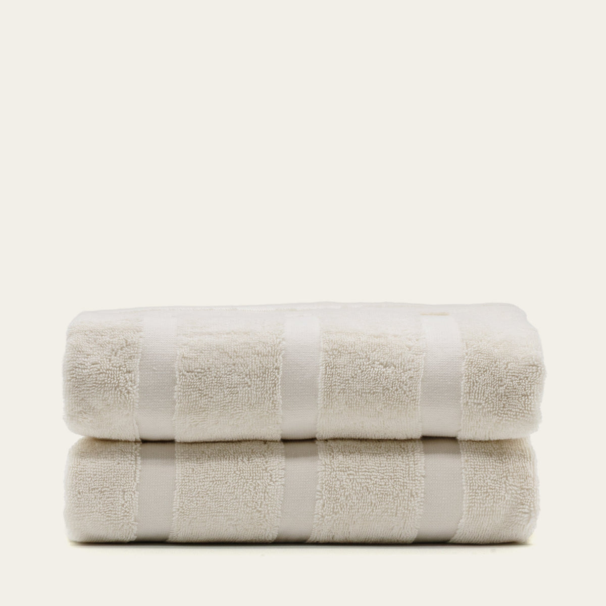 Rolled stack of cream cotton towels with embossed square texture