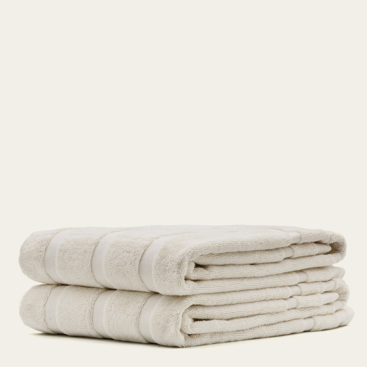 Ecru cotton towel stack with striped trim, soft terry texture