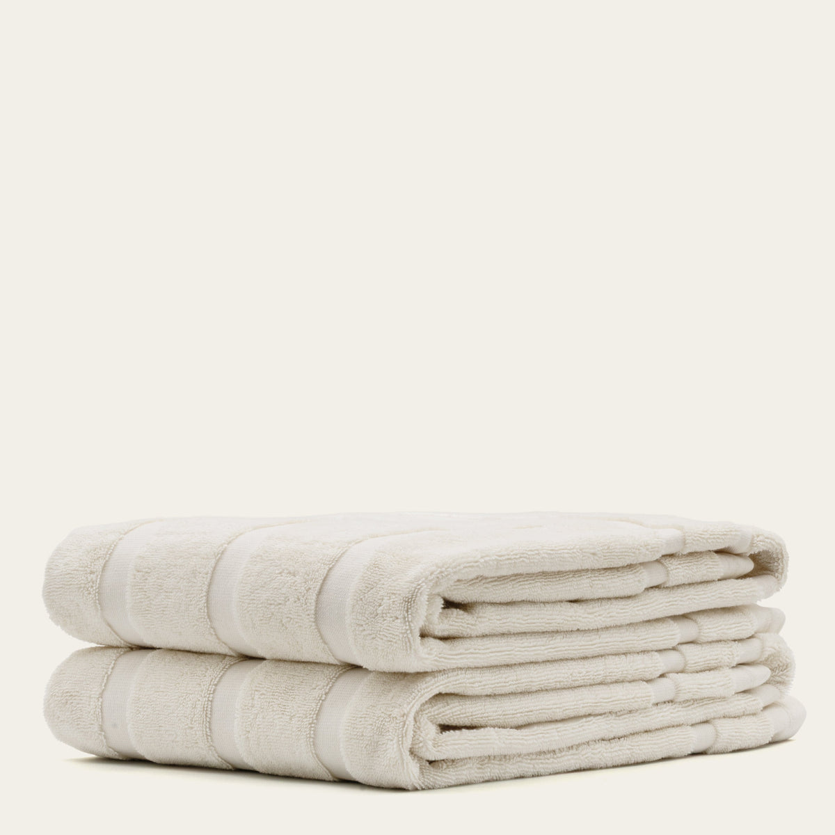 Folded off-white cotton towel stack with striped bands and soft terry pile