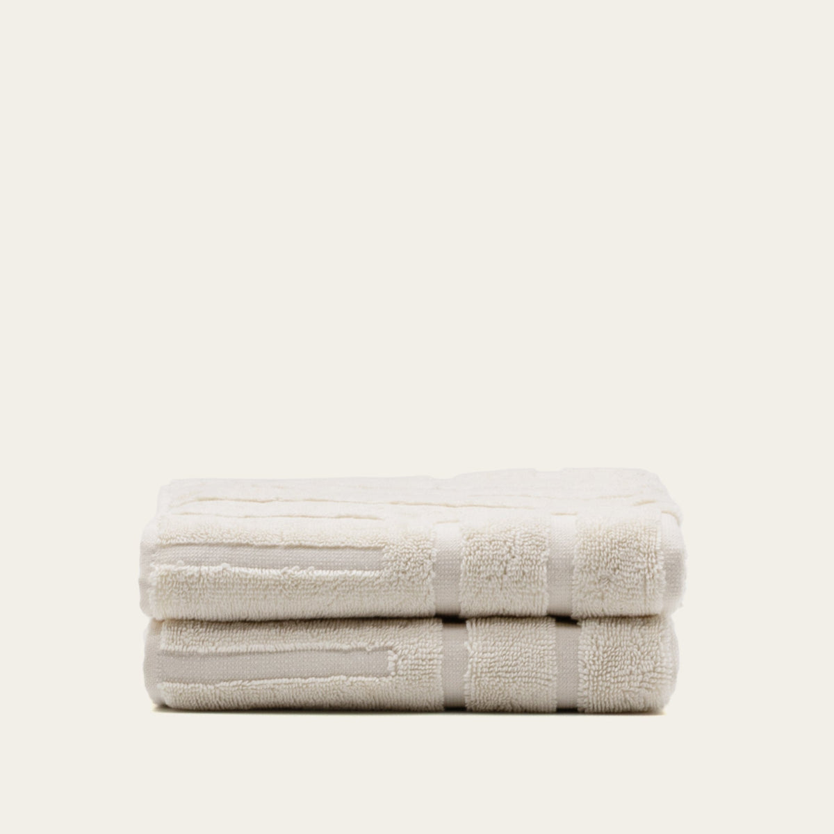Folded cream cotton towel with textured border and stitched band