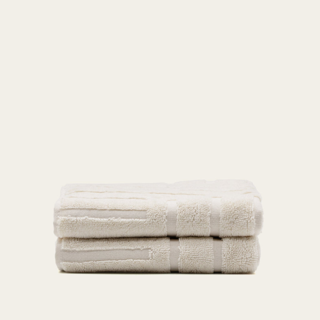 Ecru cotton bath towel folded horizontally with stitched border