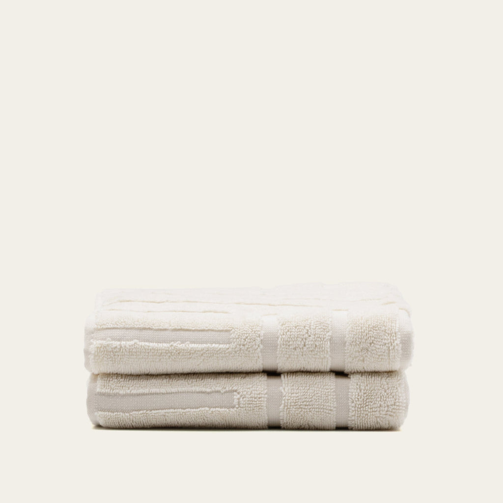 Folded ecru cotton towel set, two towels stacked with woven pattern