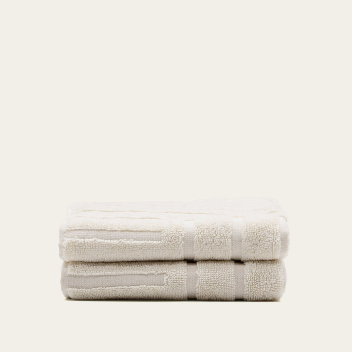 Folded ecru cotton towel set, two towels stacked with woven pattern