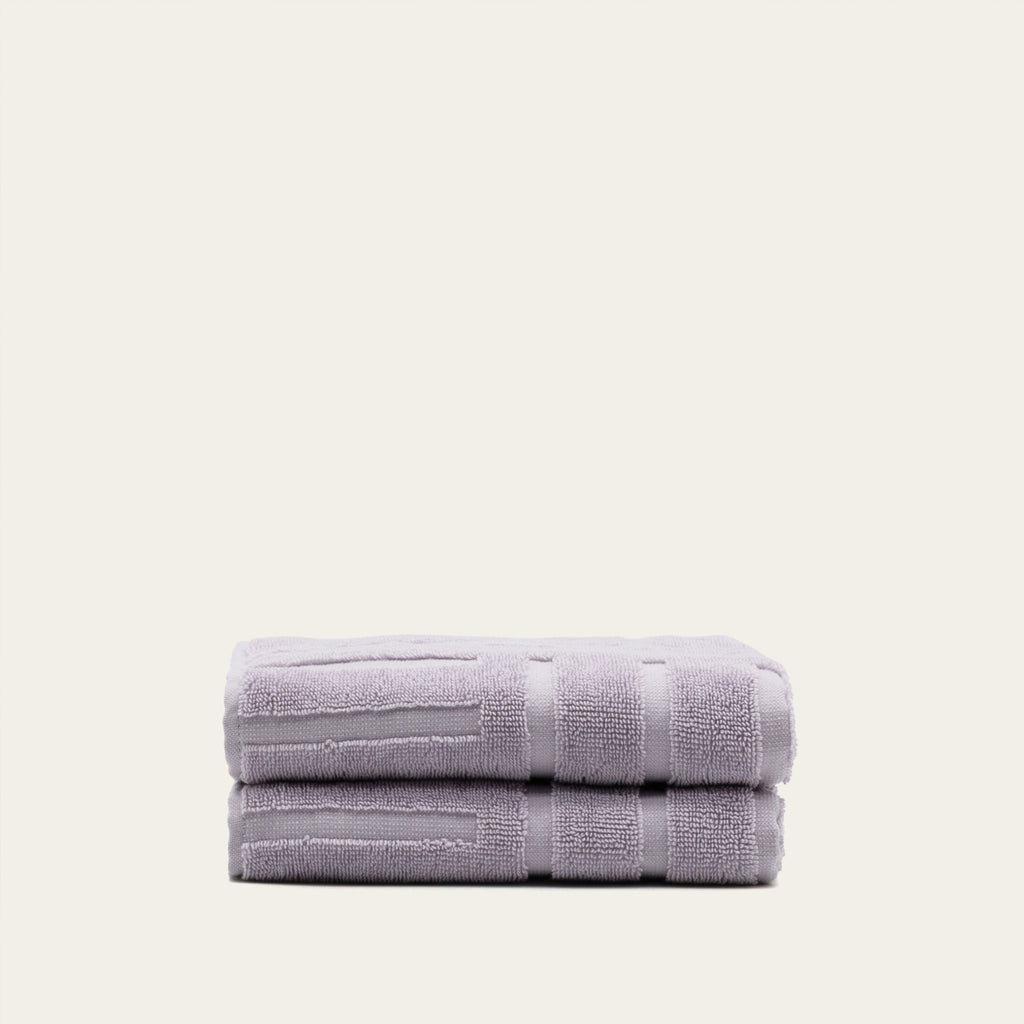 Lilac cotton towel set, folded stack with stripe bands and terry texture