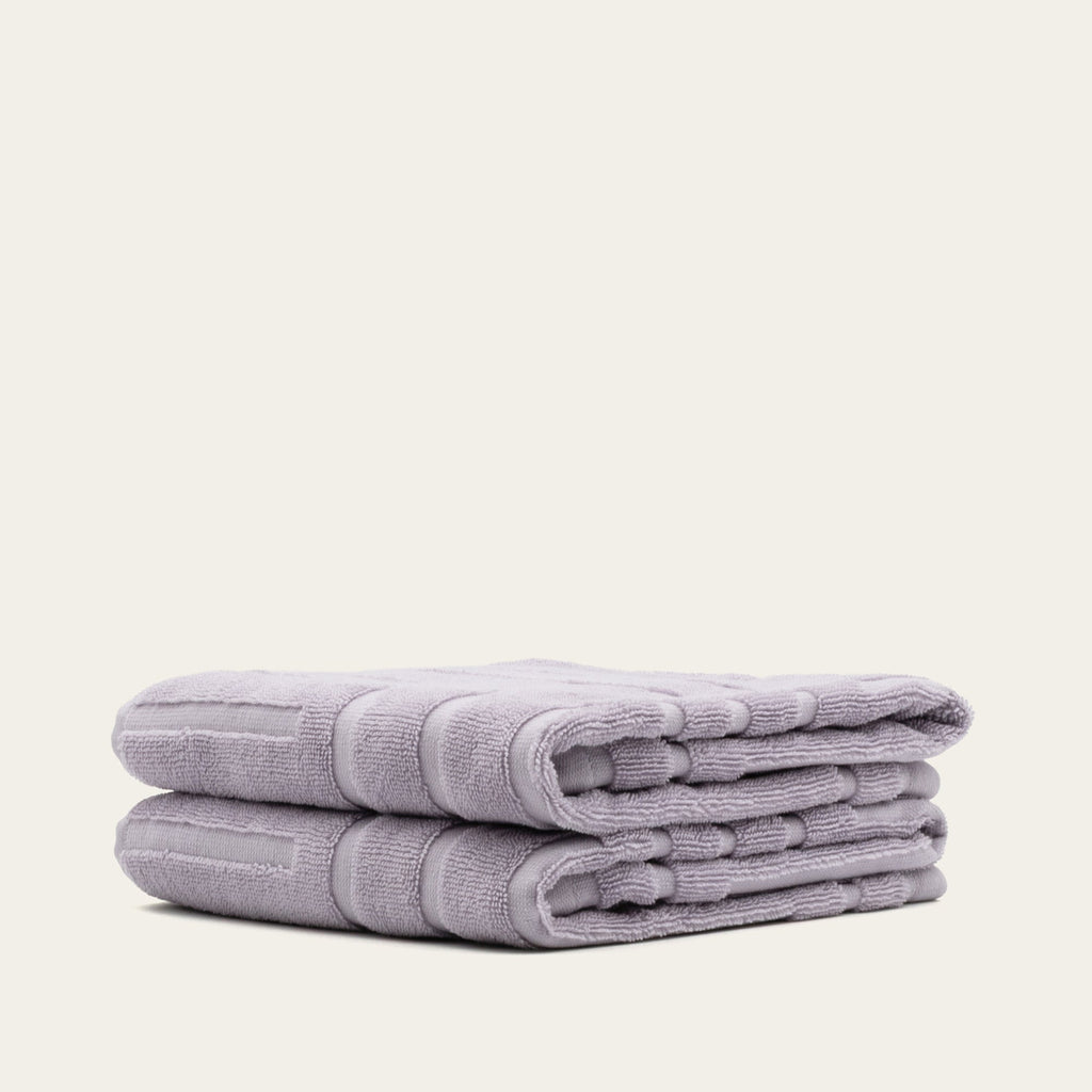 Lavender cotton towels, stacked and folded with terry texture and rolled edge