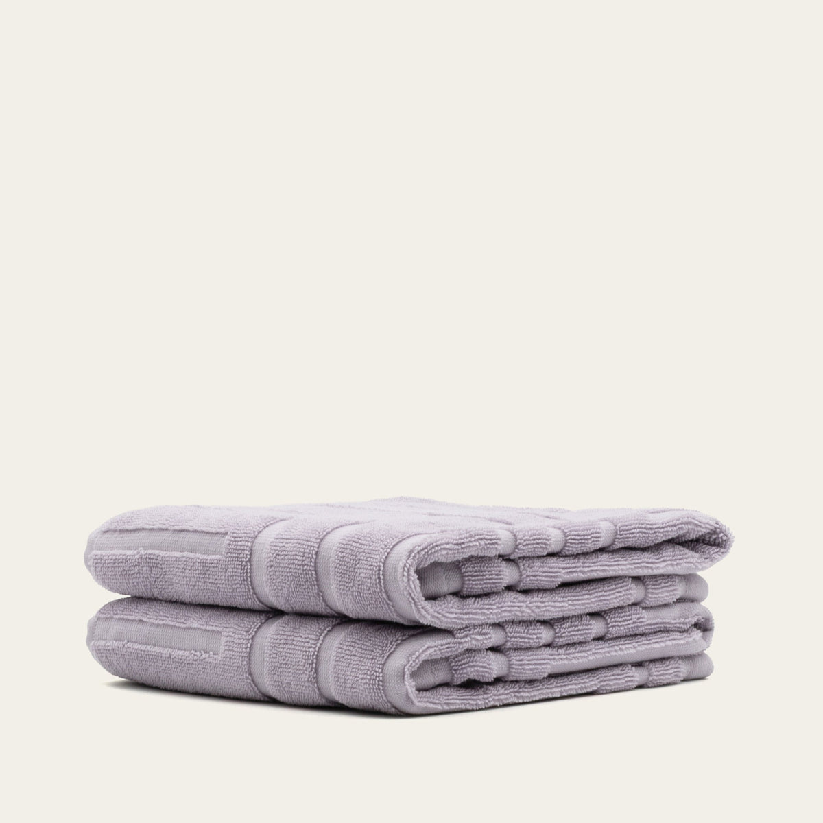 Lavender cotton towels, stacked and folded with terry texture and rolled edge