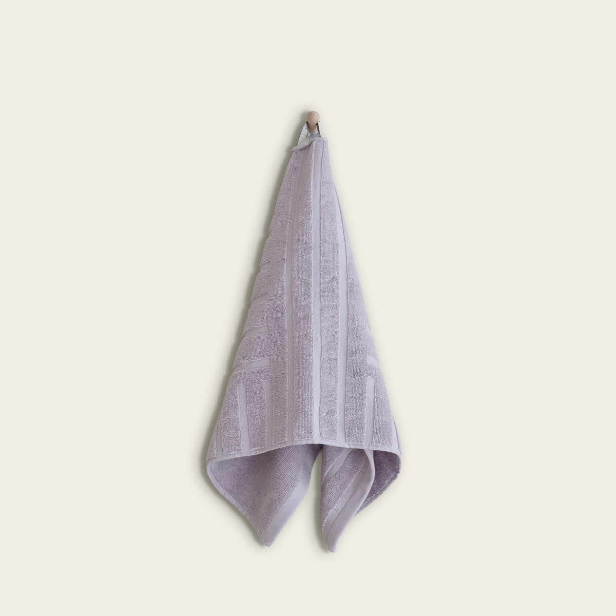 Lavender cotton towel hanging, featuring vertical stitched trim and terry loops