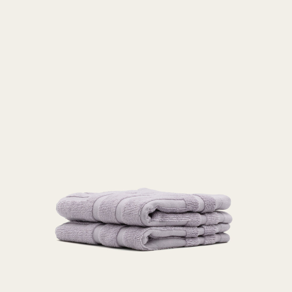 Lavender cotton towels, neatly folded stack with layered edges and terry texture
