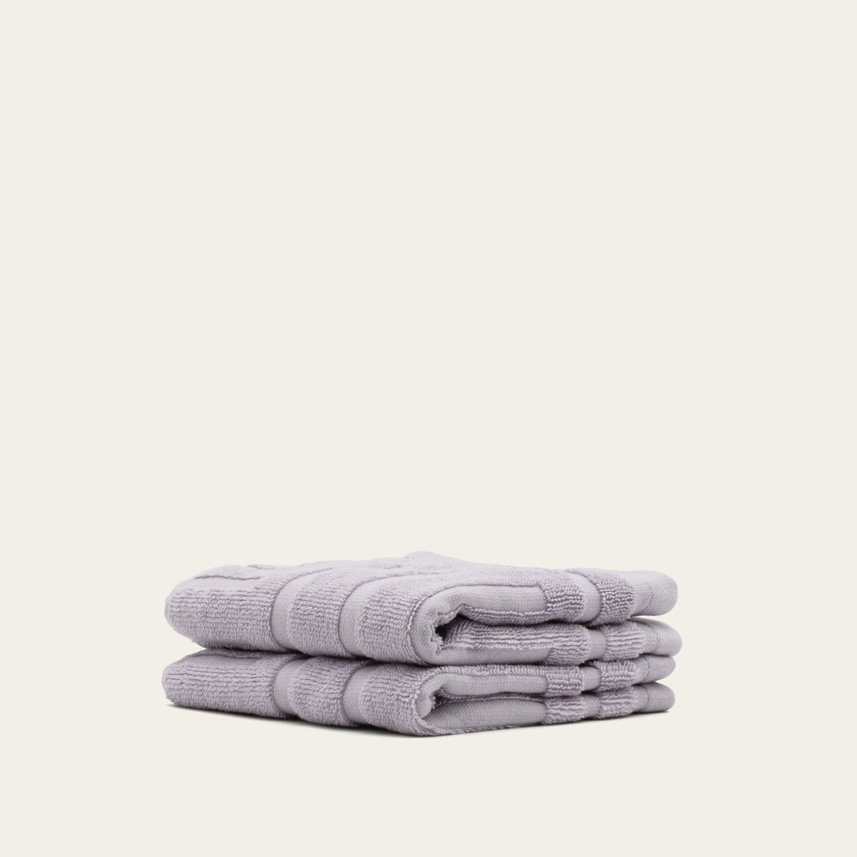 Lavender cotton towels, neatly folded stack with layered edges and terry texture