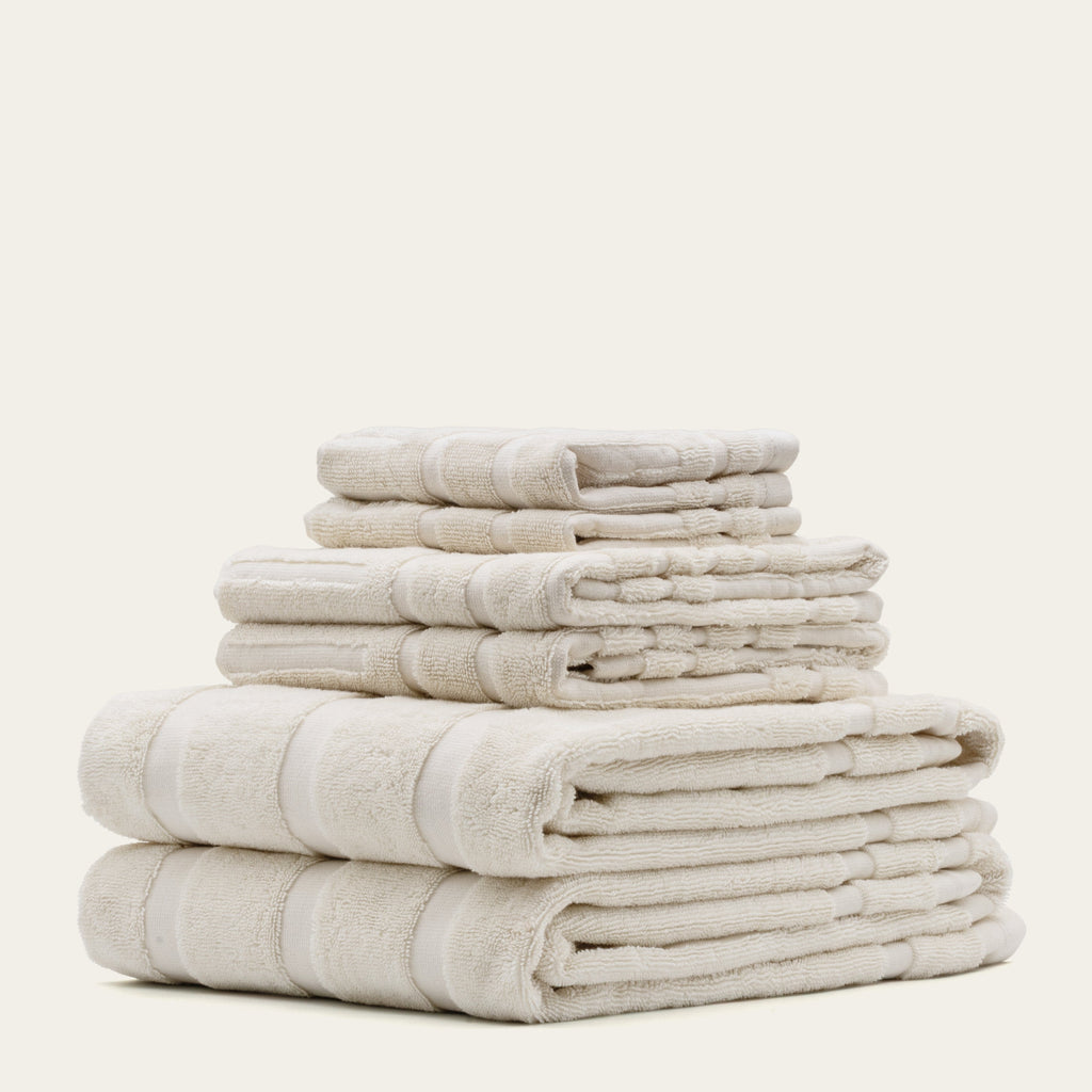 Set of folded ecru cotton towels stacked in tall pile